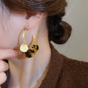 Close-up of retro leopard print hoop earrings with golden charms on a model