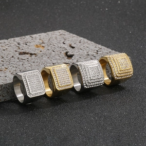 Dettaglio di anelli hip hop quadrati con zirconi incastonati su roccia vulcanica