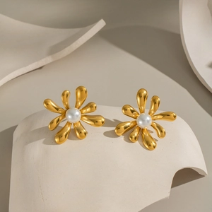 Elegant gold flower stud earrings with central white pearls on a minimalist background