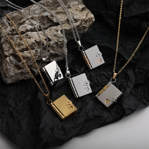 Detailed view of book-shaped heart pendants on necklaces in gold and silver finishes
