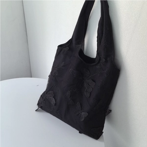 Detail of delicate black butterfly embroidery on lightweight mesh tote bag fabric