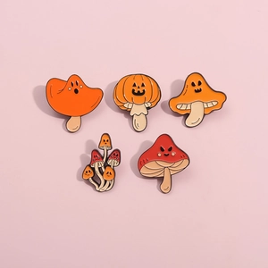 Close-up of five Halloween mushroom enamel pins with pumpkin and ghost faces on pink background