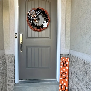 Close-up of Halloween porch decor with ghost wreath and orange BOO wooden sign