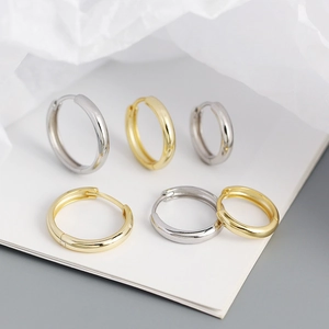 Macro view of minimalist round hoop earrings in polished gold and silver finishes