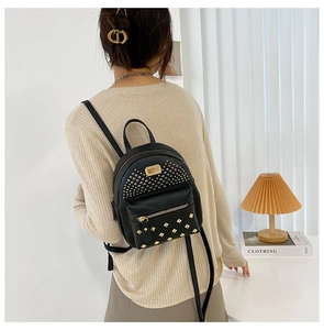 Back view of model wearing a black faux leather mini backpack with gold rivets and studs
