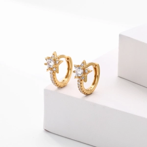 Detail view of gold star hoop earrings with clear crystals on a white pedestal