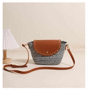 Detail view of woven crossbody bag with brown leather flap and gold stud accents