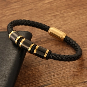 Detail of men's braided black leather bracelet with gold magnetic clasp on wood