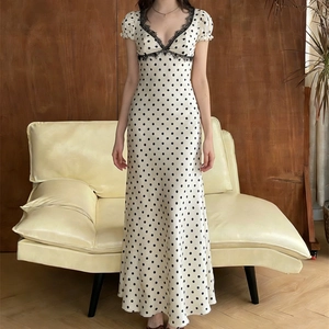 Dettaglio di un abito bianco a pois con scollo a V in pizzo nero e maniche a sbuffo