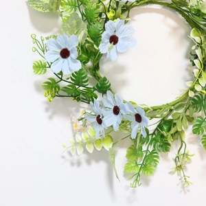 Detailed top view of a realistic candle wreath with blue daisies and lush green fern leaves