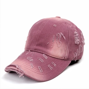 Close-up detail of distressed pink purple washed cotton baseball cap with torn fabric edges