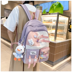 Detail of color-block school backpack with cute patches and plush duck charm accessory