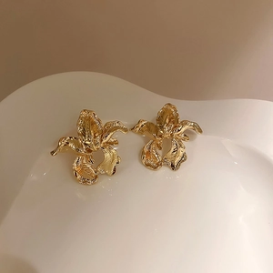 Detail of vintage irregular gold flower studs with textured petals on ceramic tray