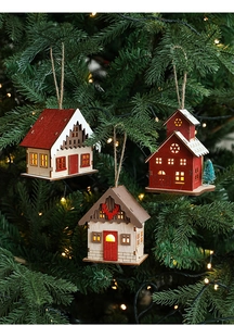 Detail of three LED wooden Christmas houses hanging on a pine tree with warm light glow