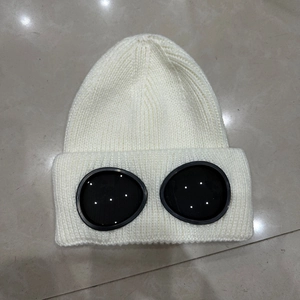 Detail of white knitted beanie featuring integrated black goggles for winter sports