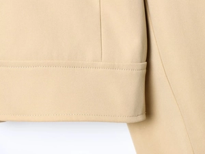 Macro shot showing high-quality double stitching on the beige woven fabric blazer cuff