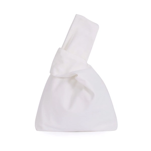 Close-up of white canvas wrist bag with unique knot design and soft fabric texture