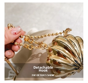 Macro detail of the detachable gold hook on a shell-shaped metallic mini handbag