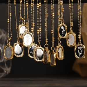 Close-up of vintage 18K gold rose flower oval pendants with floral engravings