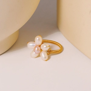 Handmade freshwater pearl flower ring with golden wire band on ceramic background