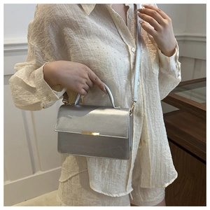 Detail showing shiny silver crossbody bag with metallic mirror finish and top handle
