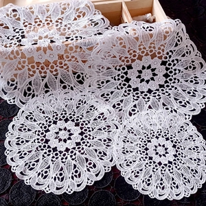 Close-up of white round lace coasters featuring intricate floral hollow embroidery detail
