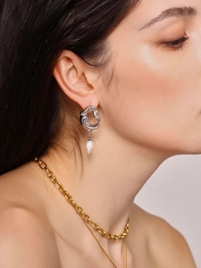 Détail de boucles d'oreilles argentées à texture lave avec perle d'eau douce blanche
