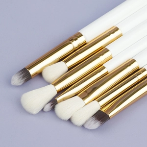 Close-up of professional 7-piece eye makeup brush set with white handles and gold ferrules