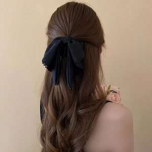 Close-up of a black lace bow hair claw clip with subtle glitter on a woman hair
