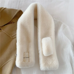 Detail of plush faux rabbit fur scarf in beige with SEZF SERVICE label on woolen coat
