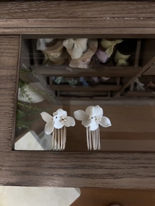 Detailed view of white ceramic flower hair combs with pearls on gold and silver metal pins