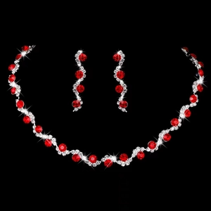 Detailed view of silver bridal necklace and red rhinestone earrings on black background