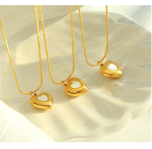 Macro view of gold snake chain necklaces with white heart shell pendants