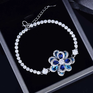 Macro view of flower-shaped bracelet with blue and white zircons on a dark display box