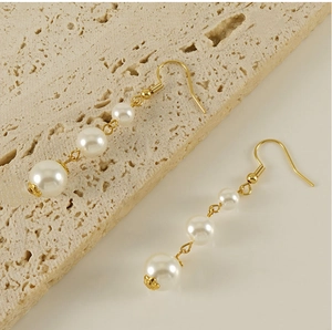 Detail of 18k gold plated drop earrings with three gradient white pearls on stone