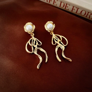 Macro shot of gold bow tassel earrings with white pearls on a dark silk backdrop
