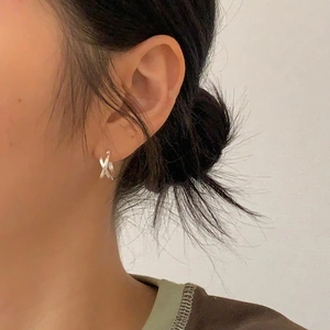 Close-up of minimalist 925 sterling silver criss-cross X earrings worn by a model