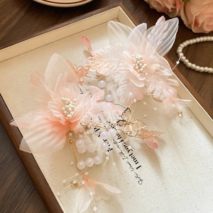 Dettaglio di fermagli per capelli fiori rosa con farfalle e nappe di perle