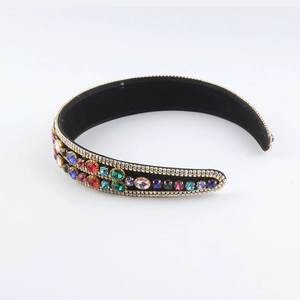 Close-up of a wide black headband featuring colorful rhinestones and gold metal settings