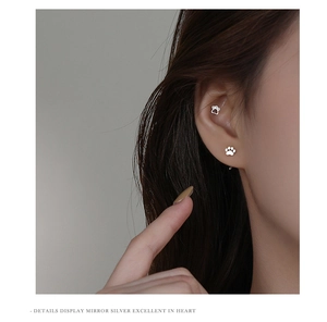Macro detail of silver cat paw stud earring shown on ear with mirror finish