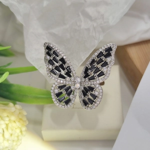 Detailed close-up of a silver butterfly ring with black gems on a beige jewelry box