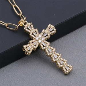 Macro shot of gold paperclip chain necklace with a cross pendant set with shiny crystals