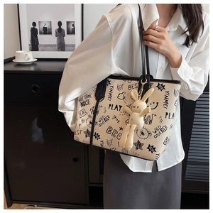 Detailed shot of large graffiti tote bag with plush rabbit charm on a female model