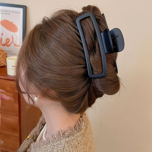 Pinza per capelli rettangolare nera opaca dal design cavo che modella capelli castani