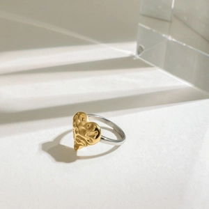 Détail d'une bague coeur bicolore avec texture dorée martelée et anneau argent
