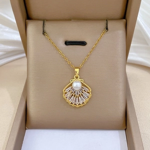 Detail of gold shell pendant with pearl and tapered baguette cubic zirconia stones