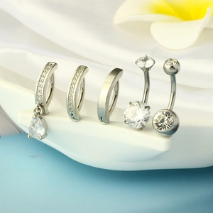 Detail view of five stainless steel belly rings with cubic zirconia on white display
