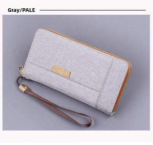 Détail de la pochette en toile gris pâle avec sangle marron et fermeture éclair dorée