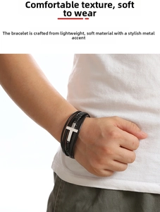 Close-up of a multilayer braided black leather bracelet with a silver metal cross clasp