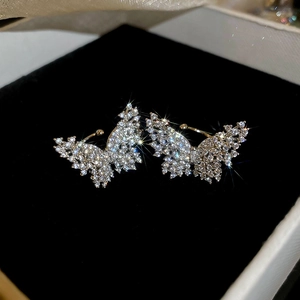Macro shot of gold butterfly ear cuffs with sparkling crystals on black velvet